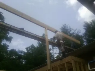 Carpenter setting a ridge beam over a new addition frame — Ice Dam Removal by Roofing Brothers in Kawkawlin