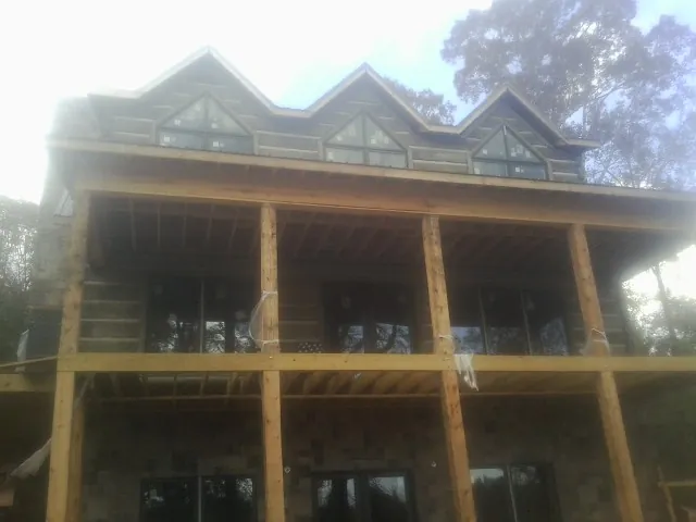 Dormers and porch framing on a large log home under construction — Roof Coating work by our crew in Kawkawlin