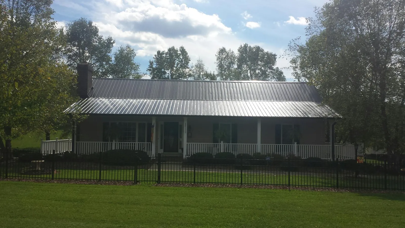 Gray metal roof on a brick ranch with a full width front porch — Gutter Guard Installation work by our crew in Kawkawlin